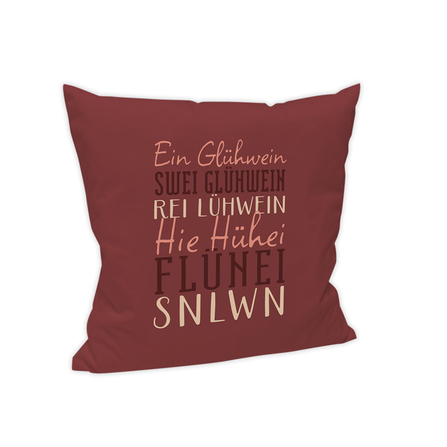 Der Hintergrund des Kissens ist in einem dunklen Rotton gehalten. In verschiedenen Farben und Schriftarten steht folgender Text: "Ein Glühwein, Swei Glühwein, Rei Glühwein, Hie Hühei, Flünei, Snlwn."