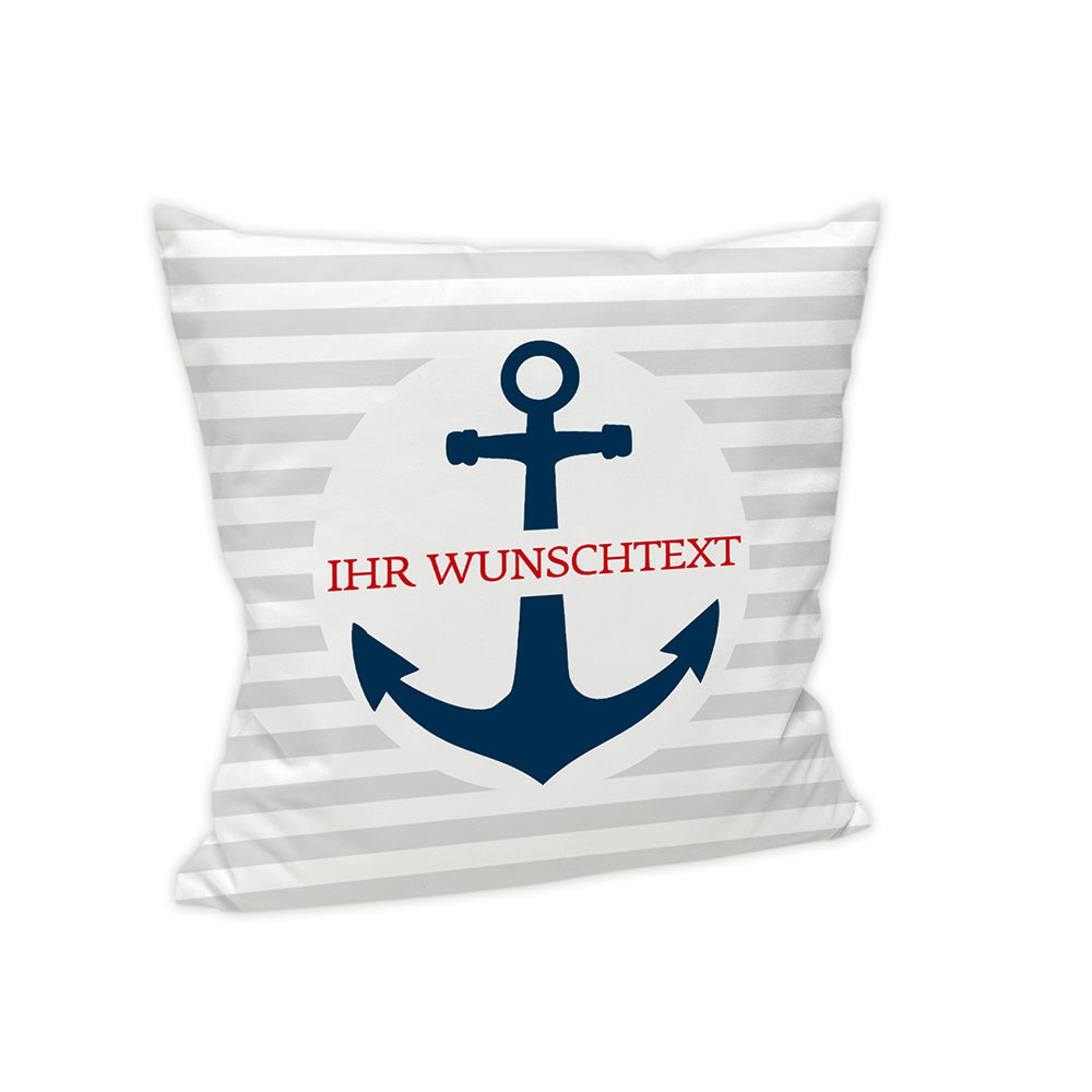 Der HIntergrund des Kissens ist Grau/Weiß gestreift. Mittig befindet sich ein weißer Kreis, in welchem sich ein dunkelblauer Anker befindet. Durch den Anker geht horizontal ein roter Schriftzug mit der Aufschrift "Ihr Wunschtext".