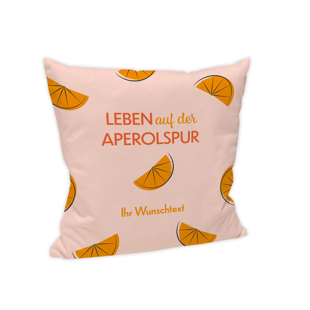 Kissen: Helles Motiv mit dem Spruch "Leben auf der Aperolspur".  Auf dem Handtuch verteilt sind Orangenstücke.