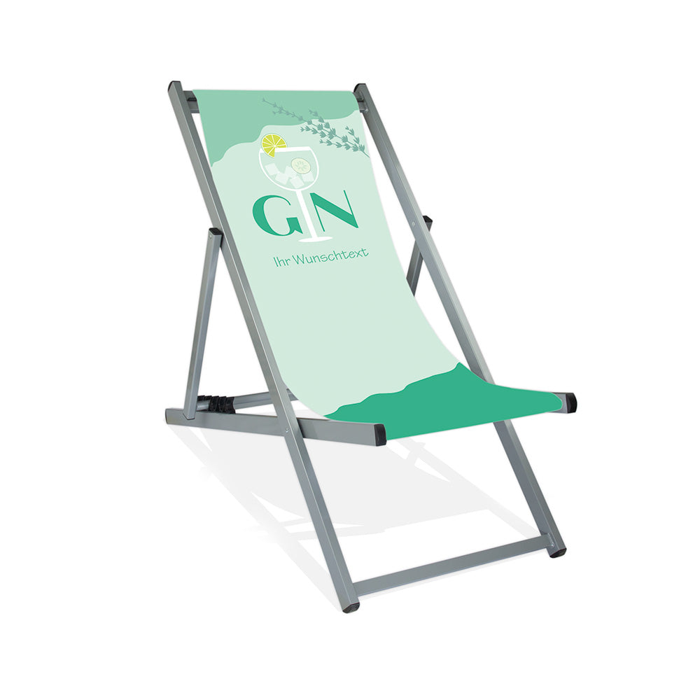 Mittig Aluminium-Liegestuhl ohne Armlehne in silber Lasur. Das Motiv auf der Stoffbahn ist Pastellmint. Im oberen Bereich steht "Gin", wobei das "i" ein Cocktailglas darstellt. Unter dem Wort "Gin" steht "Ihr Wunschtext".
Über dem gesamten Schriftzug ist rechts noch ein Kräuterzweig in Grün dargestellt.
