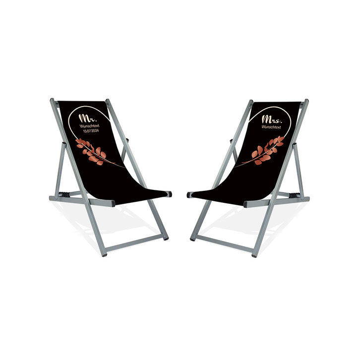 Es sind zwei Aluminium-Liegestühle ohne Armlehne in der Lasur Silber abgebildet.
Hintergrund beider Liegestühle in Schwarz. Linker Stuhl: Linke Herzhälfte in Creme und Rosé Blätter.
Rechter Stuhl rechte Herzhälfte in Creme und Rosé Blätter.
Text linker Stuhl: Mr. 
Text rechter Stuhl: Mrs.