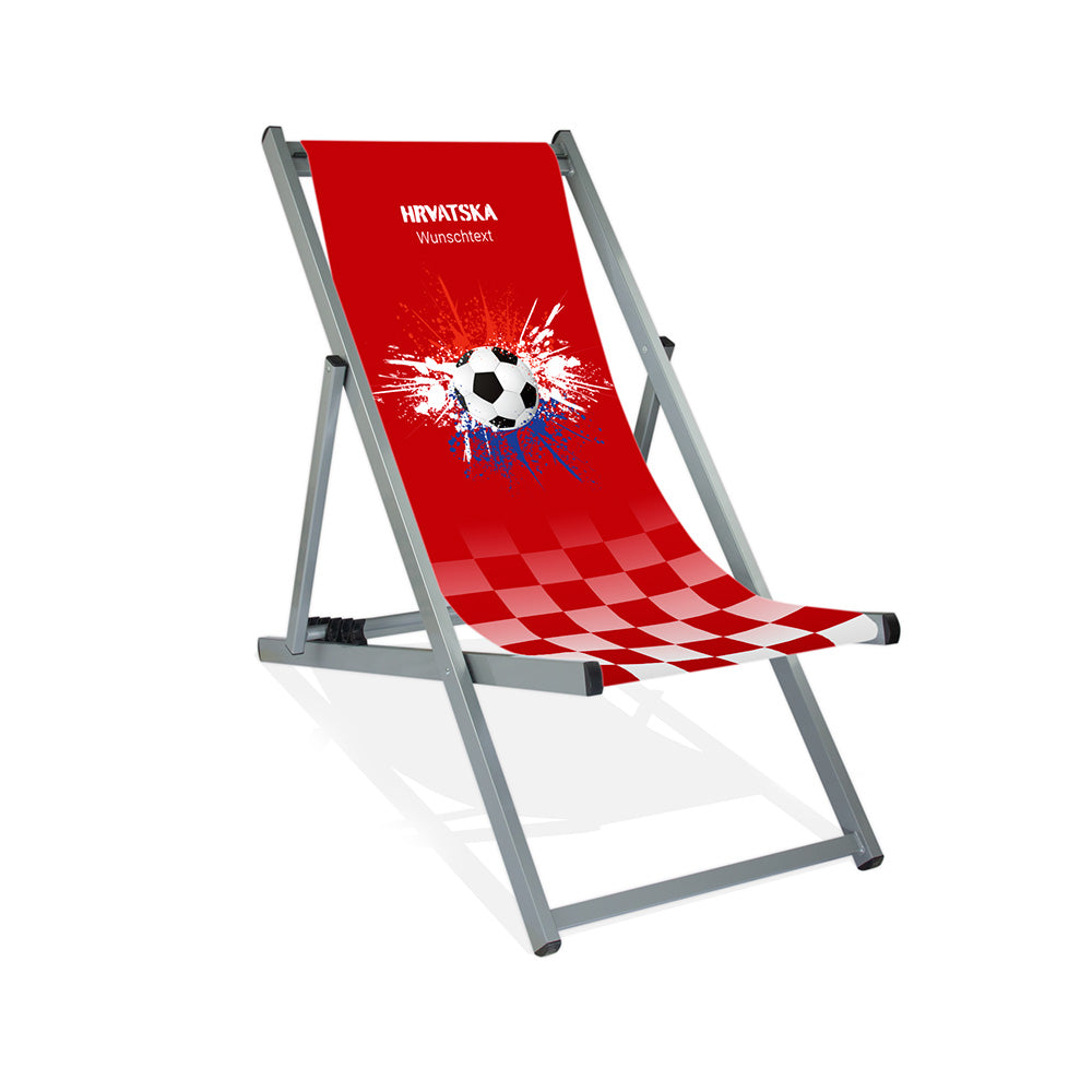Aluminiumliegestuhl in Silber im Kroatien Design zur WM 2026 mit Fußball auf rot-weiß-blauen Farbklecks und personalisierbaren Text oberhalb. Über dem Wunschtext steht "Hrvatska".
Der Hintergrund ist rot. Im unteren ein Verlauf zu rot-weiß kariert.