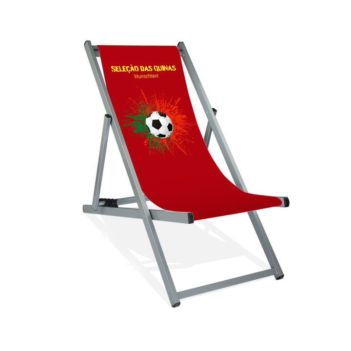 Aluminiumliegestuhl in Silber im Portugal Design zur WM 2026 mit Fußball auf grün-roten Farbklecks und personalisierbaren Text oberhalb. Über dem Wunschtext steht in gelb "Selacao das Quinas".
Der Hintergrund ist rot.