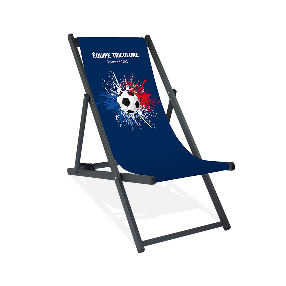 Aluminiumliegestuhl in Schwarz im Frankreich Design zur WM 2026 mit Fußball auf blau-weiß-roten Farbklecks und personalisierbaren Text oberhalb. Über dem Wunschtext steht in weiß "Equipe Tricolore".
Der Hintergrund ist blau.