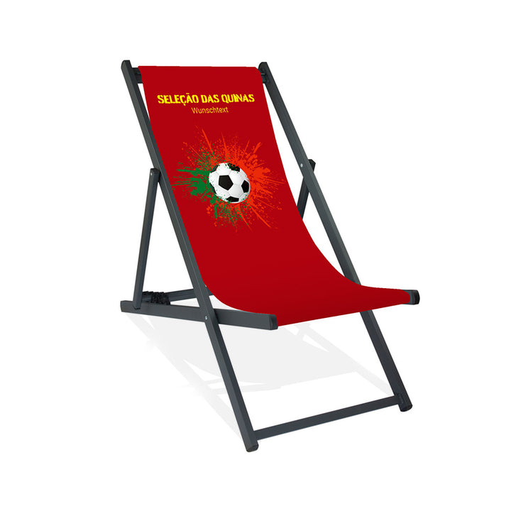 Aluminiumliegestuhl in Schwarz im Portugal Design zur WM 2026 mit Fußball auf grün-roten Farbklecks und personalisierbaren Text oberhalb. Über dem Wunschtext steht in gelb "Selacao das Quinas".
Der Hintergrund ist rot.
