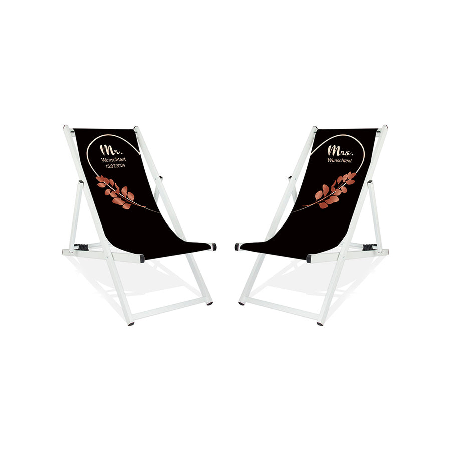 Es sind zwei Aluminium-Liegestühle ohne Armlehne in der Lasur Weiß abgebildet.
Hintergrund beider Liegestühle in Schwarz. Linker Stuhl: Linke Herzhälfte in Creme und Rosé Blätter.
Rechter Stuhl rechte Herzhälfte in Creme und Rosé Blätter.
Text linker Stuhl: Mr. 
Text rechter Stuhl: Mrs.