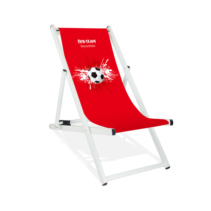 Aluminiumliegestuhl in Weiß im Österreich Design zur WM 2026 mit Fußball auf rot-weiß-roten Farbklecks und personalisierbaren Text oberhalb. Über dem Wunschtext steht in weiß "ÖFB-Team".
Der Hintergrund ist rot.
