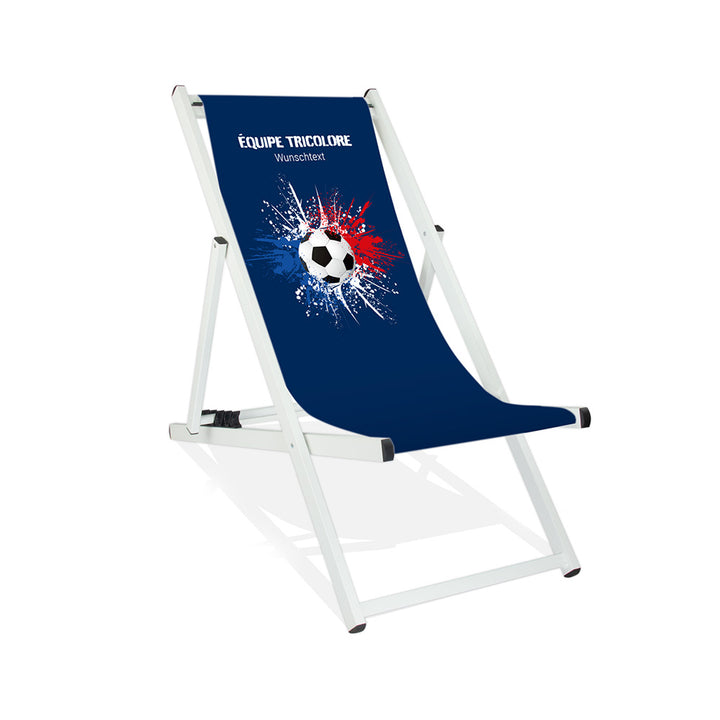 Aluminiumliegestuhl in Weiß im Frankreich Design zur WM 2026 mit Fußball auf blau-weiß-roten Farbklecks und personalisierbaren Text oberhalb. Über dem Wunschtext steht in weiß "Equipe Tricolore".
Der Hintergrund ist blau.