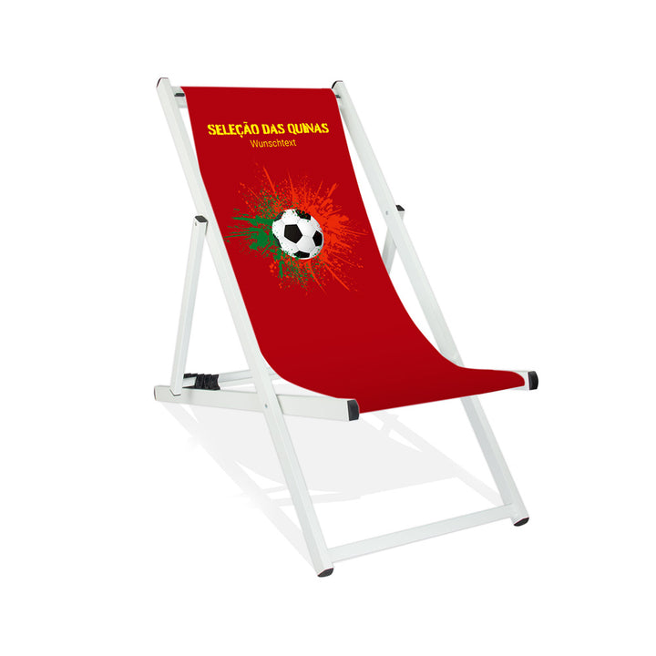 Aluminiumliegestuhl in Weiß im Portugal Design zur WM 2026 mit Fußball auf grün-roten Farbklecks und personalisierbaren Text oberhalb. Über dem Wunschtext steht in gelb "Selacao das Quinas".
Der Hintergrund ist rot.