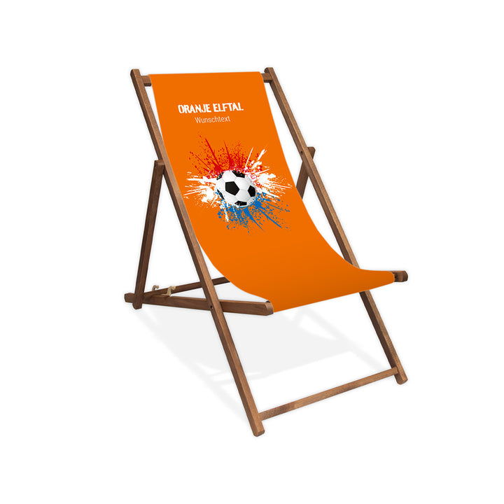Liegestuhl ohne Armlehne dunkelbraun im Niederlande Design zur WM 2026 mit Fußball auf rot-weiß-blauen Farbklecks und personalisierbaren Text oberhalb. Über dem Wunschtext steht "Oranje Elftal". Der Hintergrund ist orange.