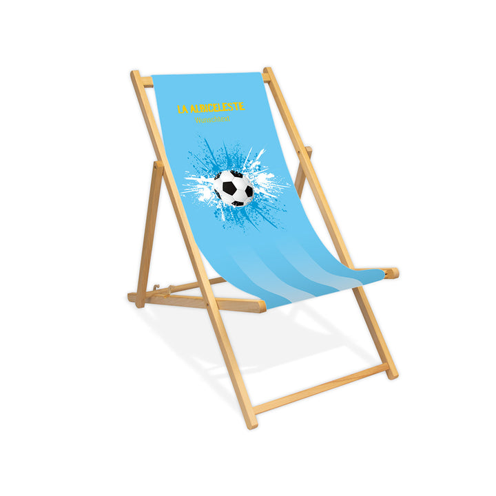 Liegestuhl ohne Armlehne farblos im Argentinien Design zur WM 2026 mit Fußball auf blau-weiß-blauen Farbklecks und personalisierbaren Text oberhalb. Über dem Wunschtext steht in gelb "La Albiceleste".
Der Hintergrund ist hellblau.