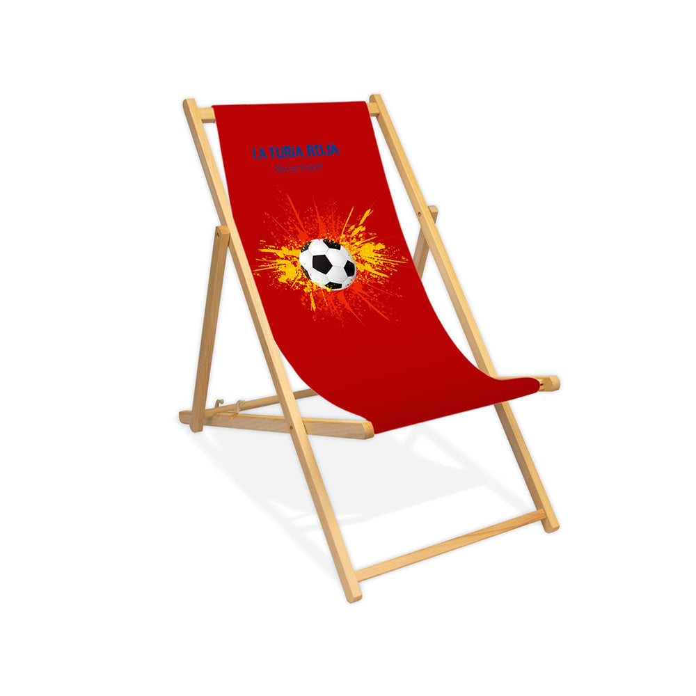 Liegestuhl ohne Armlehne farblos im Spanien Design zur WM 2026 mit Fußball auf rot-gelb-roten Farbklecks und personalisierbaren Text oberhalb. Über dem Wunschtext steht in blau "La Furia Roja".
Der Hintergrund ist rot.
