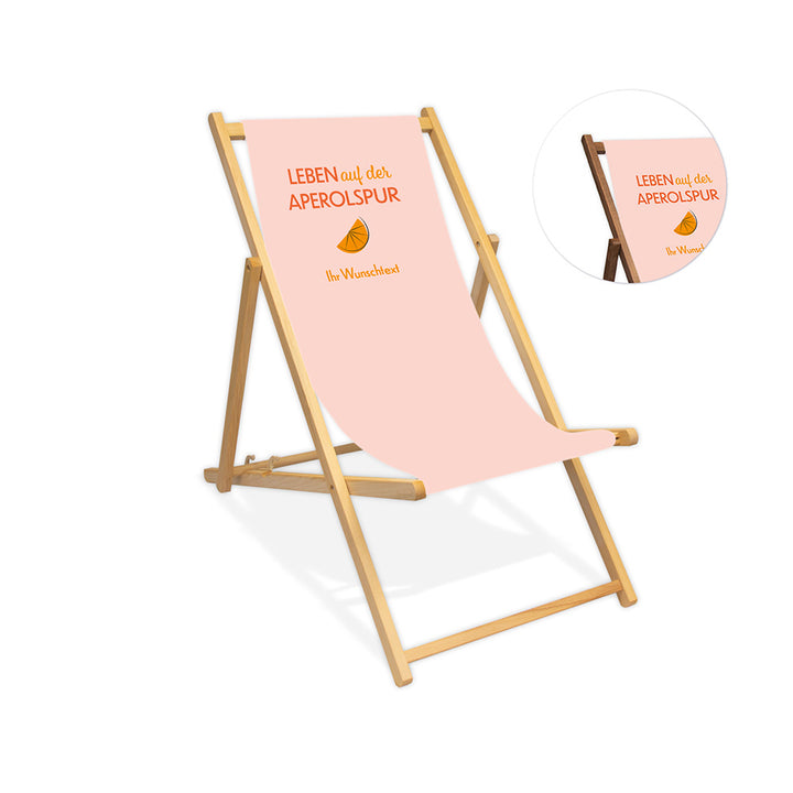 Mittig ist ein farbloser Holzliegestuhl ohne Armlehne abgebildet.
Helles Motiv mit dem Spruch "Leben auf der Aperolspur". 
Neben dem Liegestuhl ist in einem Kreis die Lasurfarbe dunkelbraun abgebildet.