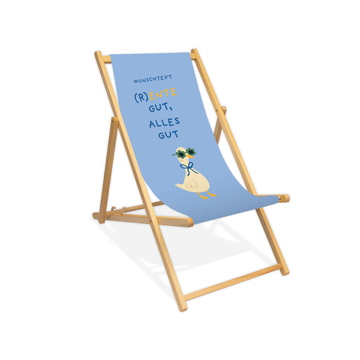Mockup eines personalisierten Holzliegestuhls ohne Armlehne mit Himmelblauen Hintergrund, Enten-Motiv mit Sonnenbrille und Schriftzug "(R)Ente gut, alles gut."
Die Lasur des Liegestuhls ist farblos.