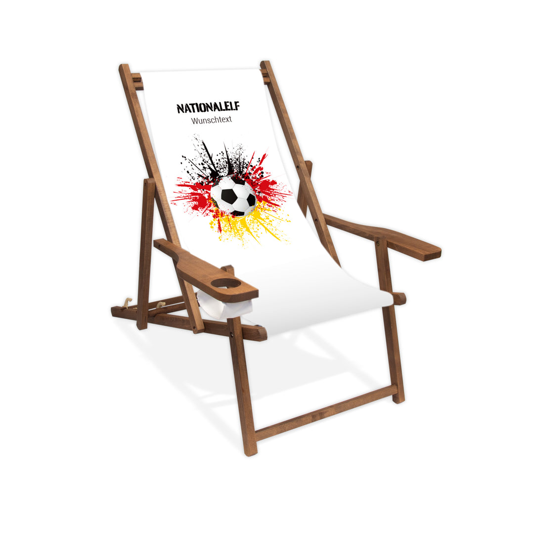 Liegestuhl mit Armlehne dunkelbraun im Deutschland Design zur WM 2026 mit Fußball auf schwarz-rot-goldenem Farbklecks und personalisierbaren Text oberhalb. Über dem Wunschtext steht "Nationalelf".
