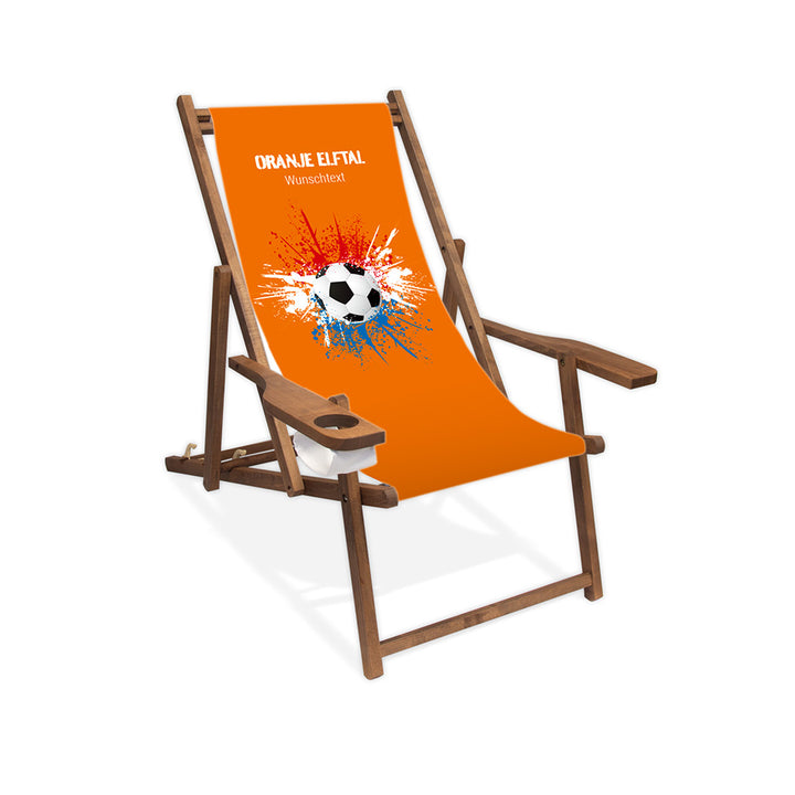 Liegestuhl mit Armlehne dunkelbraun im Niederlande Design zur WM 2026 mit Fußball auf rot-weiß-blauen Farbklecks und personalisierbaren Text oberhalb. Über dem Wunschtext steht "Oranje Elftal". Der Hintergrund ist orange.