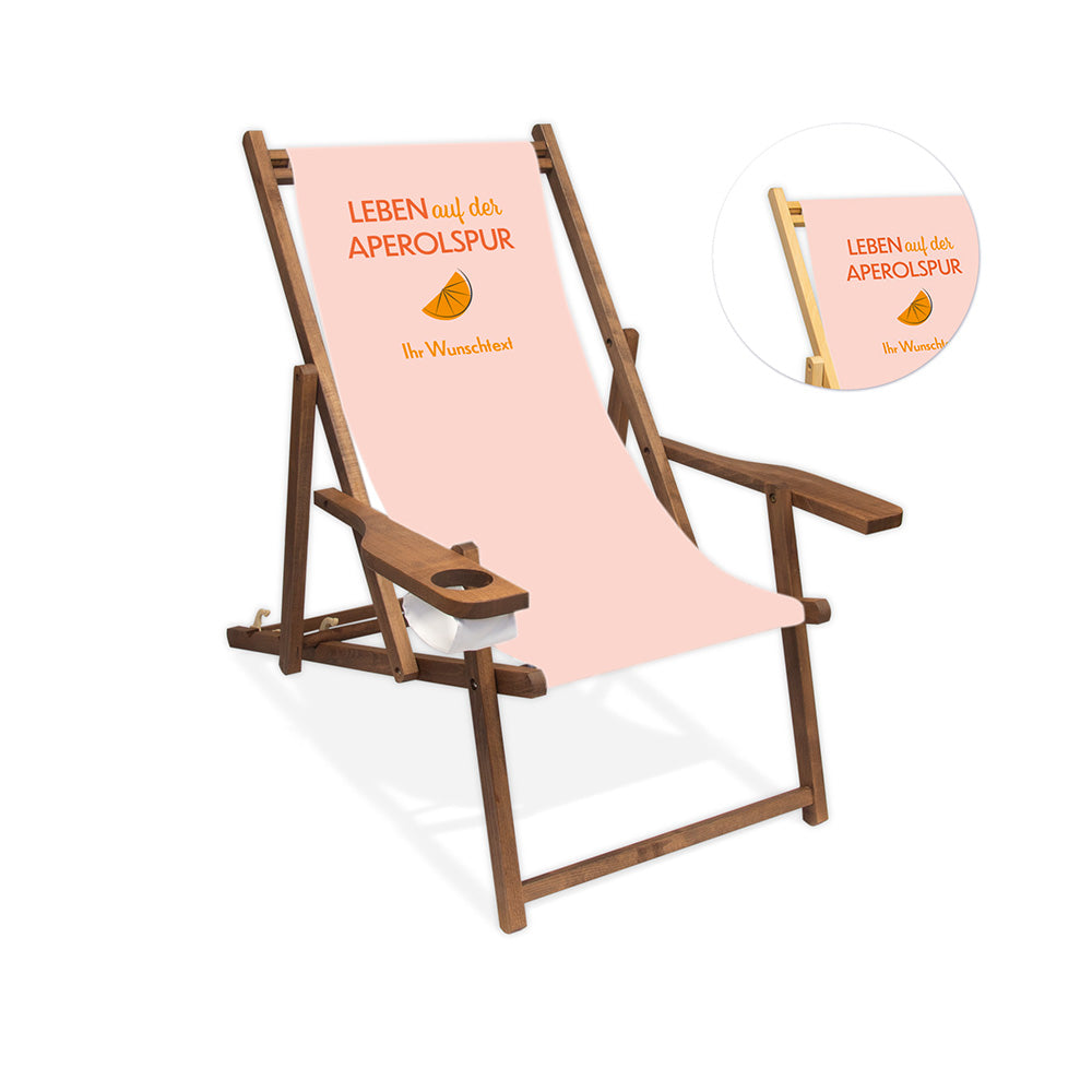 Mittig ist ein dunkelbrauner Holzliegestuhl mit Armlehne abgebildet.
Helles Motiv mit dem Spruch "Leben auf der Aperolspur". 
Neben dem Liegestuhl ist in einem Kreis die Lasurfarbe farblos abgebildet.