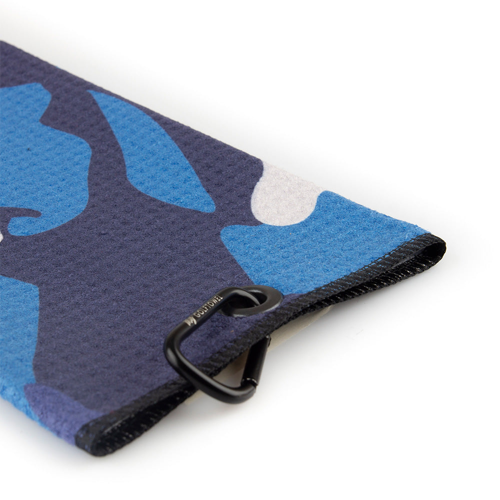 Detailfoto von der schwarzen Öse und dem Karabiner auf einem Golftowel Small mit einem Camouflagemuster in Blau.