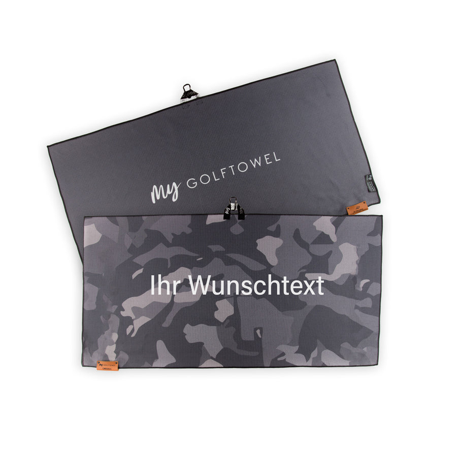 Golftowel Large in grauem Camouflage Muster. Auf dem Golftowel steht Mittig in einer weißen, serifenlosen Schrift geschrieben "Ihr Wunschtext". Die Rückseite des Golftowels ist Grau dargestellt. Hier steht mittig der Schriftzug "MyGolftowel". Im unteren Bereich befindet sich ein braunes Lederpatch und oben ist eine Schlaufe und Karabiner angebracht.