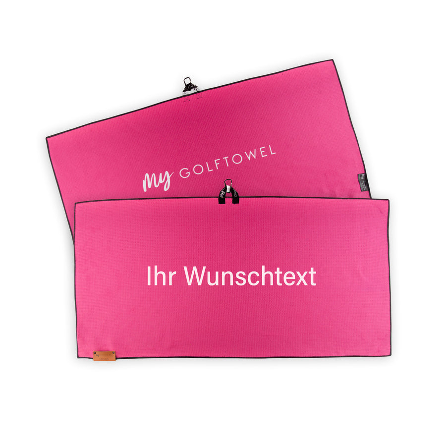 Golftowel Large in Pink. Auf dem Golftowel steht Mittig in einer weißen, serifenlosen Schrift geschrieben "Ihr Wunschtext". Die Rückseite des Golftowels ist im gleichen Pink, wie die Vorderseite dargestellt. Hier steht mittig der Schriftzug "MyGolftowel". Im unteren Bereich befindet sich ein braunes Lederpatch und oben ist eine Schlaufe und Karabiner angebracht.