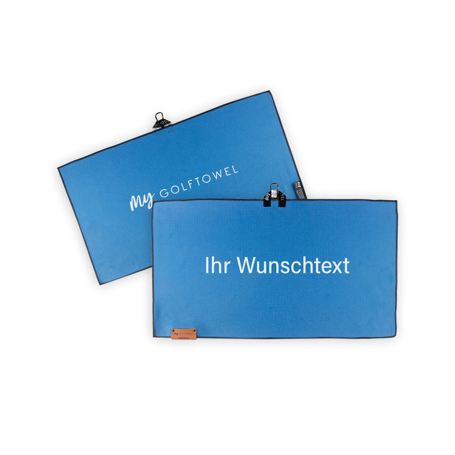 Golftowel Medium in Blau. Auf dem Golftowel steht Mittig in einer weißen, serifenlosen Schrift geschrieben "Ihr Wunschtext". Die Rückseite des Golftowels ist im gleichen Blau, wie die Vorderseite dargestellt. Hier steht mittig der Schriftzug "MyGolftowel". Im unteren Bereich befindet sich ein braunes Lederpatch und oben ist eine Schlaufe und Karabiner angebracht.