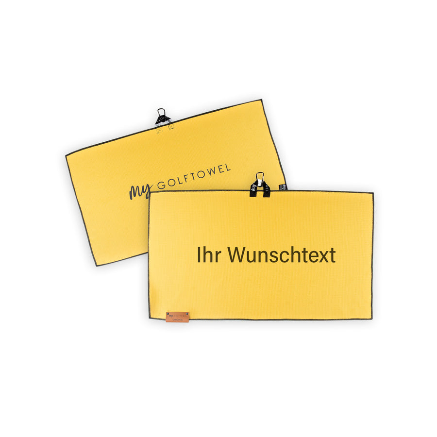 Golftowel Medium in Gelb. Auf dem Golftowel steht Mittig in einer schwarzen, serifenlosen Schrift geschrieben "Ihr Wunschtext". Die Rückseite des Golftowels ist im gleichen Gelb, wie die Vorderseite dargestellt. Hier steht mittig der Schriftzug "MyGolftowel". Im unteren Bereich befindet sich ein braunes Lederpatch und oben ist eine Schlaufe und Karabiner angebracht.