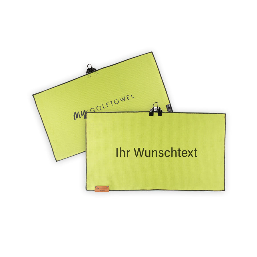Golftowel Medium in Lemon. Auf dem Golftowel steht Mittig in einer schwarzen, serifenlosen Schrift geschrieben "Ihr Wunschtext". Die Rückseite des Golftowels ist im gleichen Farbton, wie die Vorderseite dargestellt. Hier steht mittig der Schriftzug "MyGolftowel". Im unteren Bereich befindet sich ein braunes Lederpatch und oben ist eine Schlaufe und Karabiner angebracht.