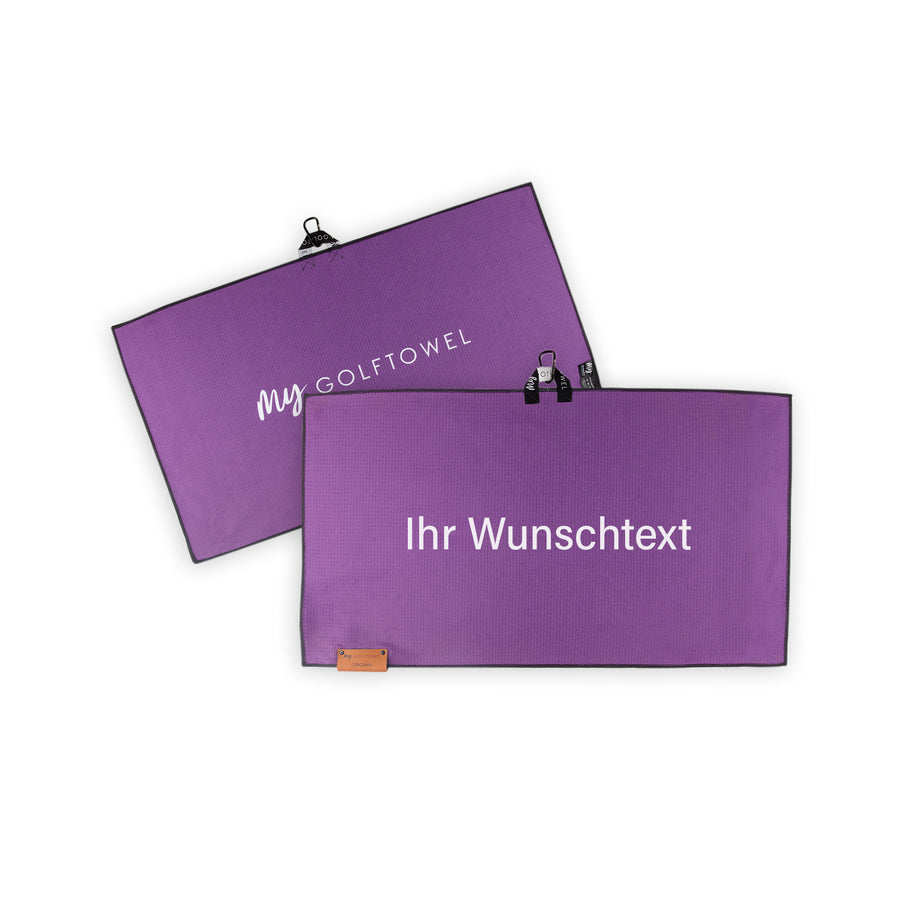 Golftowel Medium in Lila. Auf dem Golftowel steht Mittig in einer weißen, serifenlosen Schrift geschrieben "Ihr Wunschtext". Die Rückseite des Golftowels ist im gleichen Lila, wie die Vorderseite dargestellt. Hier steht mittig der Schriftzug "MyGolftowel". Im unteren Bereich befindet sich ein braunes Lederpatch und oben ist eine Schlaufe und Karabiner angebracht.