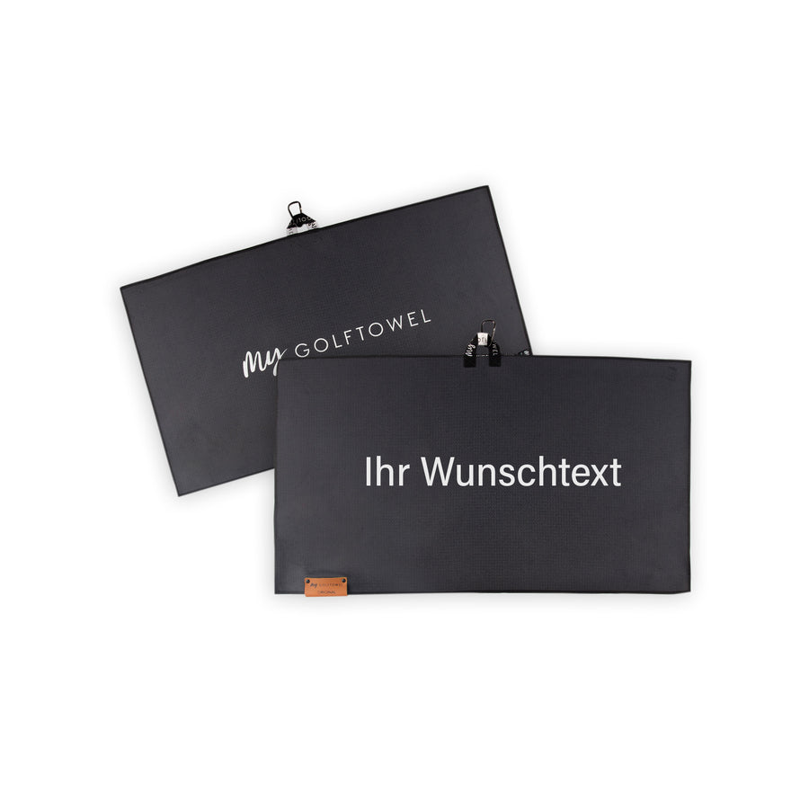Golftowel Medium in Schwarz. Auf dem Golftowel steht Mittig in einer weißen, serifenlosen Schrift geschrieben "Ihr Wunschtext". Die Rückseite des Golftowels ist im gleichen Schwarz, wie die Vorderseite dargestellt. Hier steht mittig der Schriftzug "MyGolftowel". Im unteren Bereich befindet sich ein braunes Lederpatch und oben ist eine Schlaufe und Karabiner angebracht.