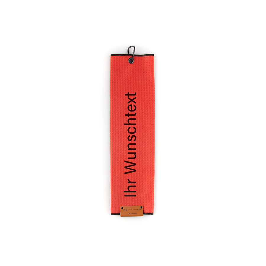 Gefaltetes Golftowel in Rot. Auf dem Golftowel steht von unten nach oben geschrieben der Text "Ihr Wunschtext" in Schwarz. Im unteren Bereich befindet sich ein braunes Lederpatch und oben ist ein schwarzer Karabiner in einer schwarzen Öse angebracht.