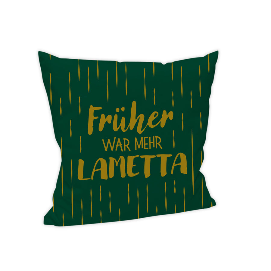 Der Hintergrund des Kissens ist in einem dunkleren Grün gehalten. In der Mitte steht auf 3 Zeilen verteilt und zwei verschiedenen Schriftarten "Früher war mehr Lametta". Die Schrift ist dabei in Gold gehlaten. Auch sind Vertikale Linien als abstraktes Lametta über den gesamten Hintergrund verteilt.